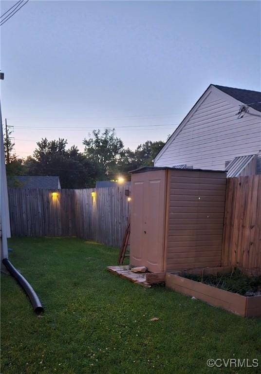 yard at dusk featuring a storage unit and an outdoor structure