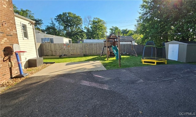 view of yard featuring a playground, a shed, a patio, and an outbuilding