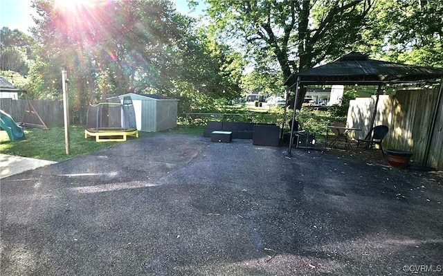 view of parking featuring a gazebo, fence, and a storage unit