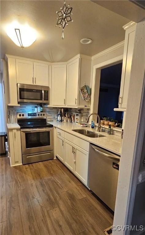 kitchen with stainless steel appliances, a sink, light countertops, and white cabinets