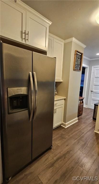 kitchen with stainless steel fridge with ice dispenser, white cabinetry, crown molding, baseboards, and dark wood-type flooring