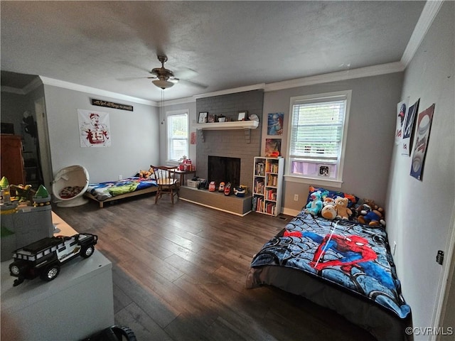 bedroom featuring ornamental molding, wood finished floors, a fireplace, a ceiling fan, and a textured ceiling