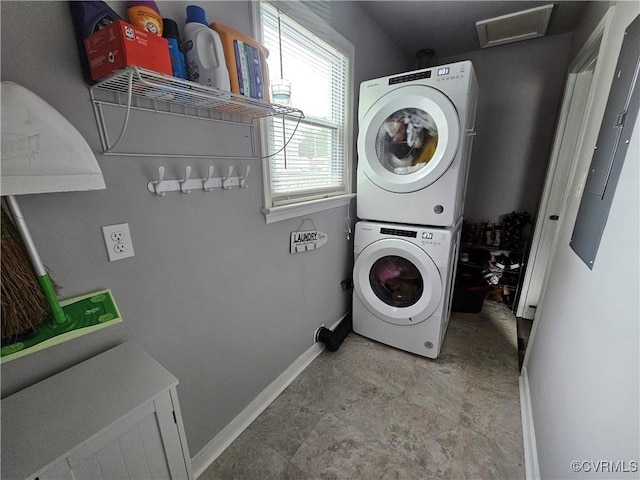 laundry room featuring stacked washer / drying machine, baseboards, and attic access