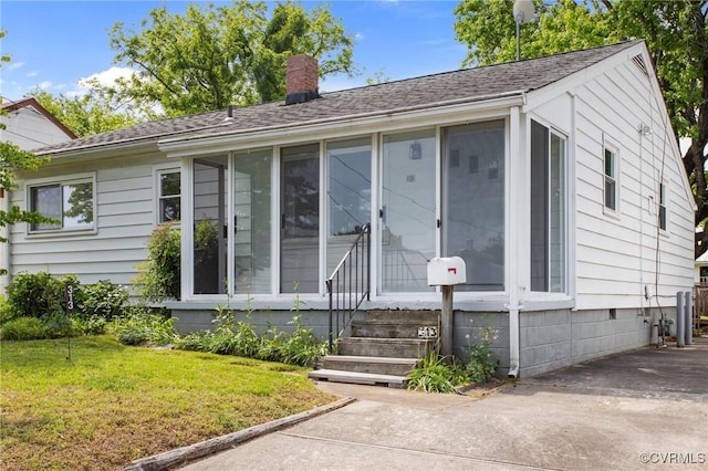 ranch-style home with a sunroom, a chimney, a front yard, and crawl space