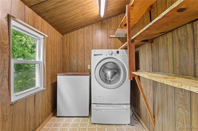 laundry area with healthy amount of natural light, wood walls, washing machine and clothes dryer, and wooden ceiling