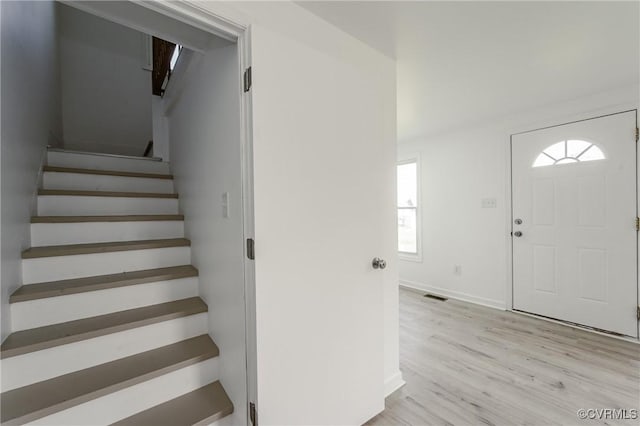 entryway with stairway, light wood-style flooring, and baseboards