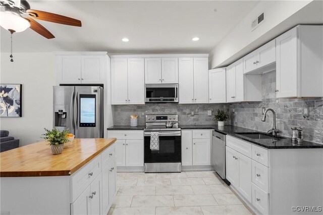 1216 N 30th St, Richmond, VA 23223 - kitchen featuring stainless steel appliances, wood counters, white cabinets, decorative backsplash, and recessed lighting