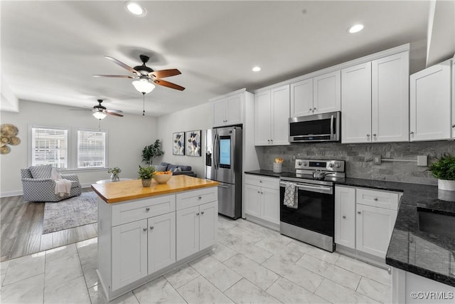 1216 N 30th St, Richmond, VA 23223 - kitchen featuring stainless steel appliances, a ceiling fan, butcher block countertops, light marble finish floors, and tasteful backsplash