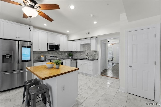 1216 N 30th St, Richmond, VA 23223 - kitchen featuring appliances with stainless steel finishes, ceiling fan, wood counters, decorative backsplash, and white cabinets