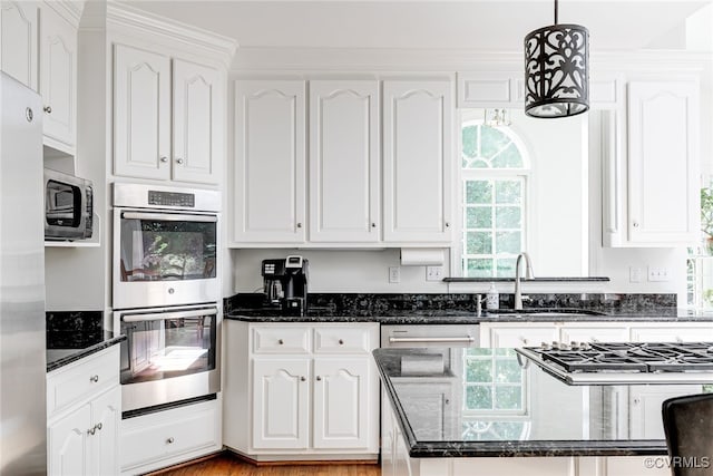 9905 Carrington Pl, Henrico, VA 23238 - kitchen featuring appliances with stainless steel finishes, a sink, white cabinets, dark stone countertops, and decorative light fixtures