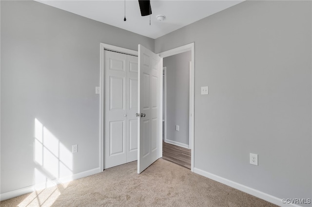 unfurnished bedroom with carpet, a closet, baseboards, and a ceiling fan
