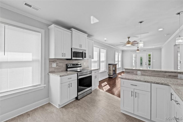 kitchen with stainless steel appliances, ornamental molding, white cabinets, baseboards, and ceiling fan