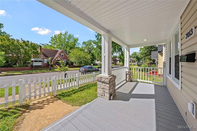 wooden deck featuring covered porch and fence