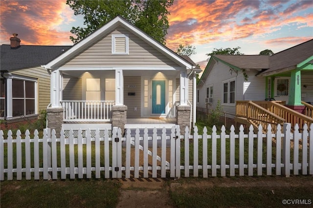 bungalow-style home with a porch and a fenced front yard