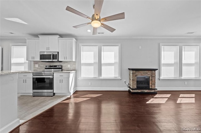 kitchen with appliances with stainless steel finishes, crown molding, baseboards, wood-type flooring, and white cabinetry