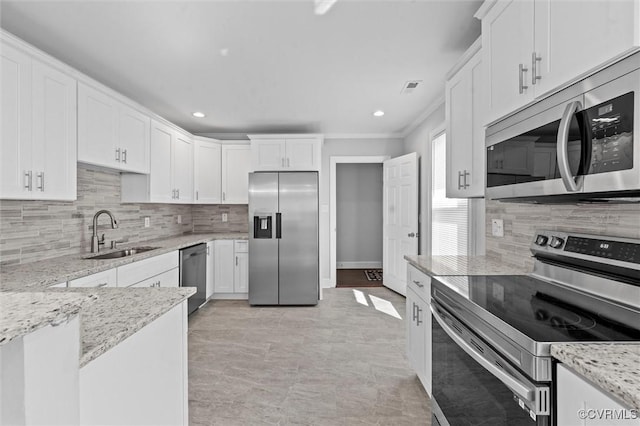 kitchen with stainless steel appliances, a sink, backsplash, white cabinetry, and light stone countertops