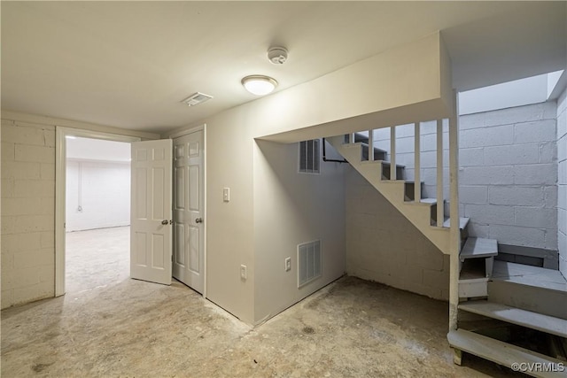 finished basement featuring stairway and concrete block wall