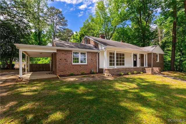 view of front of property with brick siding, a front yard, a chimney, and a carport