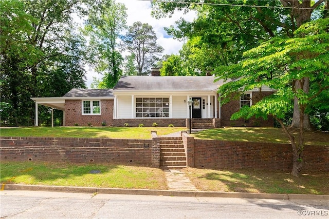 ranch-style home with a front yard, brick siding, a chimney, and a carport