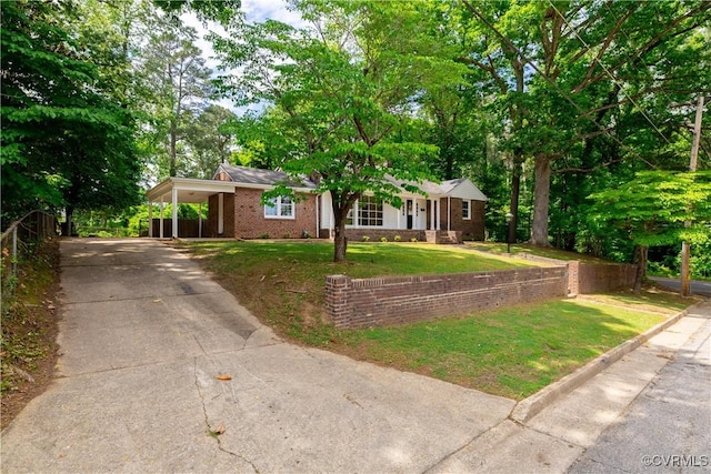 view of front facade with a front yard, concrete driveway, brick siding, and a carport