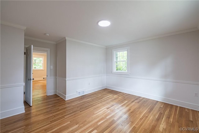 spare room with light wood-type flooring, healthy amount of natural light, ornamental molding, and baseboards