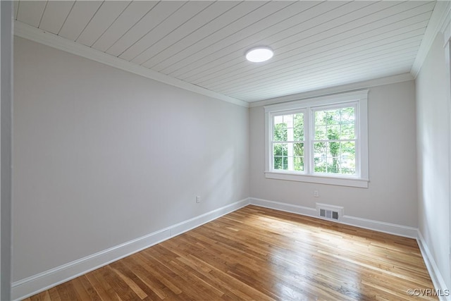 spare room featuring ornamental molding, baseboards, light wood-style floors, and wood ceiling