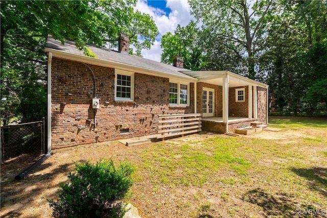 back of property with a chimney, french doors, and brick siding