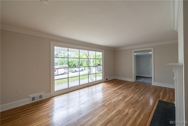 unfurnished living room with wood finished floors, baseboards, and crown molding