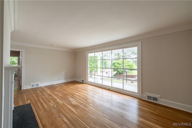 unfurnished room featuring light wood-type flooring, ornamental molding, baseboards, and a fireplace