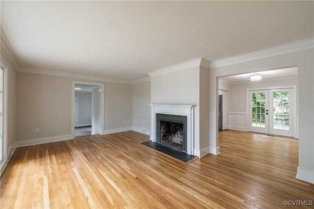 unfurnished living room featuring light wood-style flooring, a fireplace, ornamental molding, and baseboards