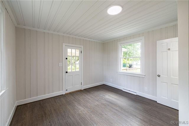 empty room with dark wood-type flooring, plenty of natural light, baseboards, and a baseboard heating unit