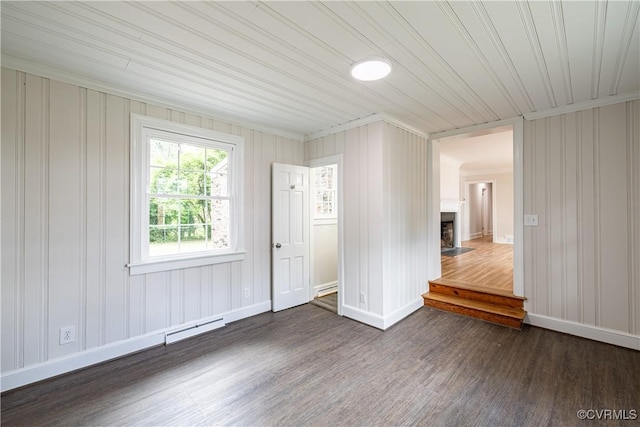 spare room featuring dark wood-style floors, ornamental molding, baseboards, and a fireplace with flush hearth