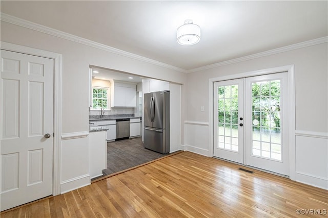 entryway with light wood-style floors, crown molding, french doors, and a sink