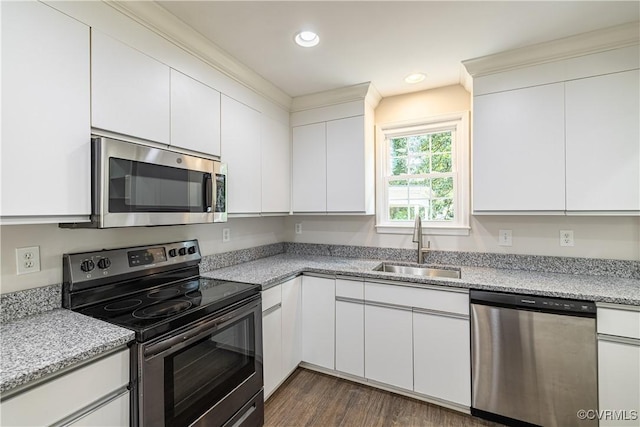 kitchen with appliances with stainless steel finishes, a sink, white cabinetry, dark wood-type flooring, and recessed lighting