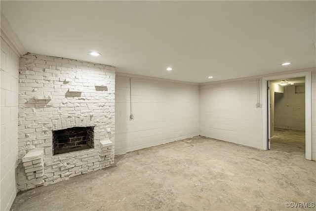 finished basement featuring a stone fireplace, recessed lighting, and concrete block wall