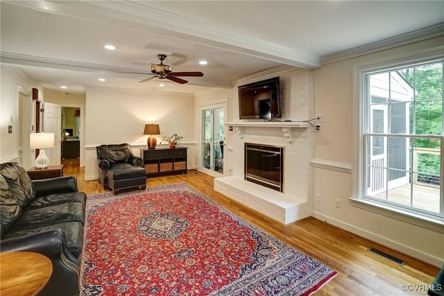 living room featuring wood finished floors, a fireplace, crown molding, a ceiling fan, and recessed lighting