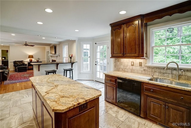 kitchen with dishwasher, a sink, plenty of natural light, crown molding, and open floor plan