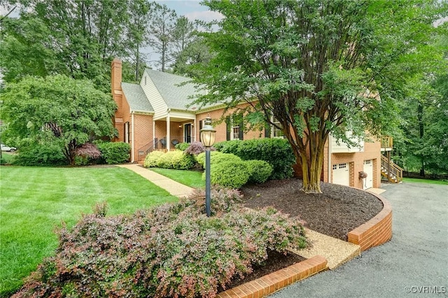 view of front of home featuring an attached garage, a chimney, driveway, a front yard, and stairs