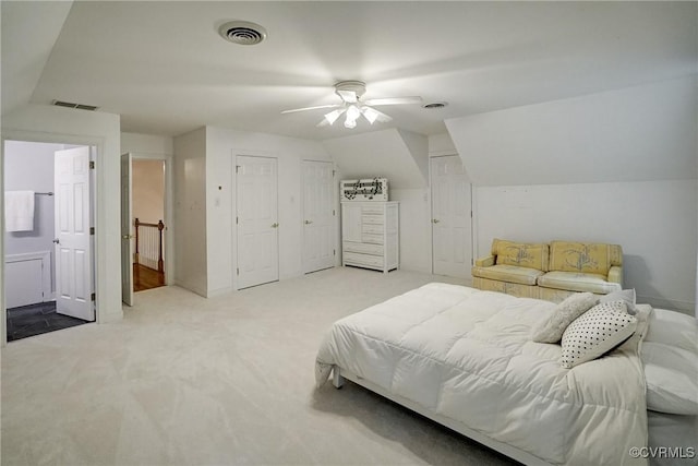 bedroom with lofted ceiling, carpet, two closets, ensuite bathroom, and ceiling fan