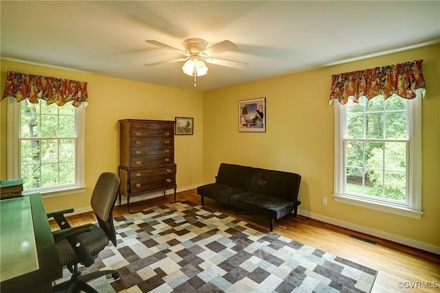 home office with healthy amount of natural light, wood finished floors, a ceiling fan, and baseboards