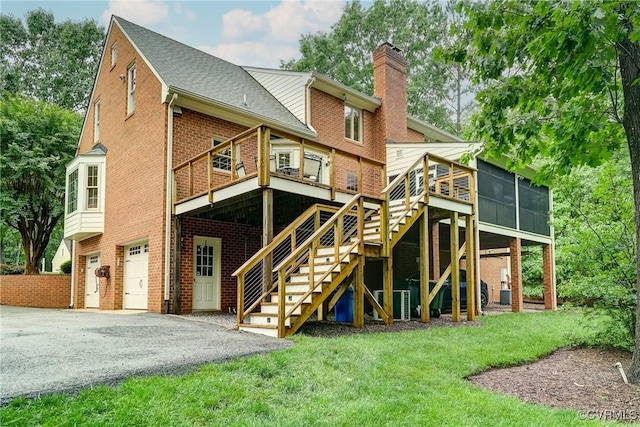 back of property with a chimney, brick siding, an attached garage, driveway, and stairs