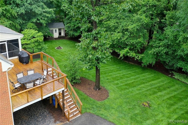 view of green lawn featuring a deck, an outdoor structure, outdoor dining area, and stairway