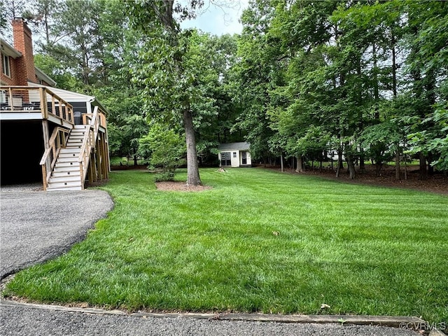 view of grassy yard with stairway, an outbuilding, a storage unit, and a deck