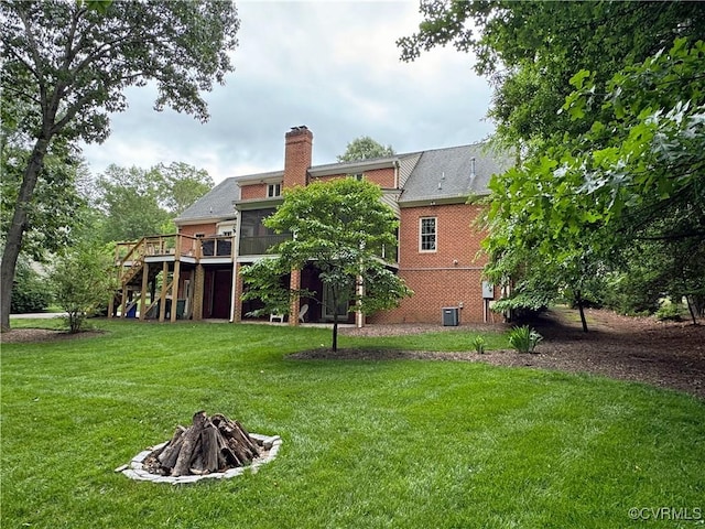 rear view of house with stairs, a fire pit, a deck, a lawn, and a chimney