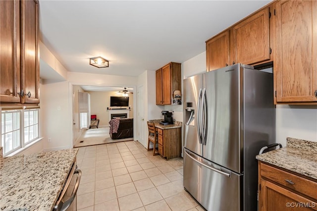 kitchen featuring stainless steel appliances, a ceiling fan, brown cabinets, and light tile patterned floors
