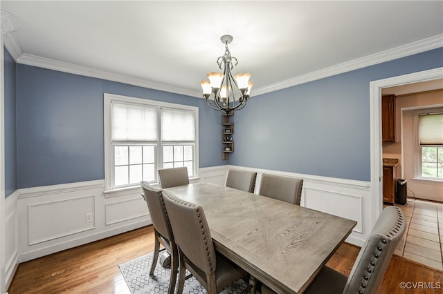 dining room featuring a chandelier, ornamental molding, a wainscoted wall, and wood finished floors