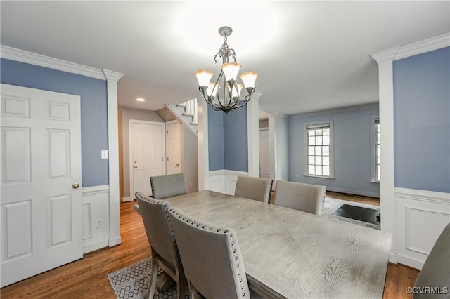 dining space featuring stairway, a chandelier, wainscoting, wood finished floors, and ornamental molding