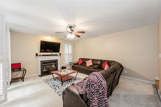 living room featuring light carpet, a ceiling fan, baseboards, and a fireplace with flush hearth