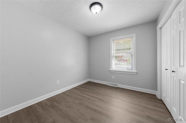7408 Newbys Ct, Chesterfield, VA 23832 - unfurnished bedroom with a closet, dark wood-type flooring, baseboards, and a textured ceiling