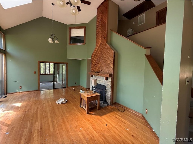 unfurnished living room with high vaulted ceiling, ceiling fan, wood finished floors, and a skylight